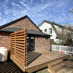 Modern wooden deck with privacy screen and small steps leading to backyard