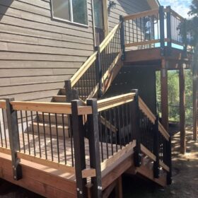 Multi-level wooden deck with black metal railings and stairs connecting different levels