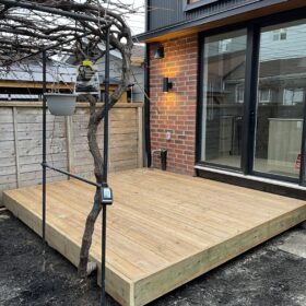 Cozy wooden deck in the backyard with a grill and dining area