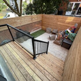 Wooden deck in the backyard featuring a children's play area with toys and seating arrangements.