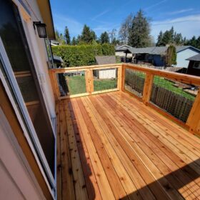 Beautifully finished wooden deck on a sunny day with a clear blue sky, next to a house.