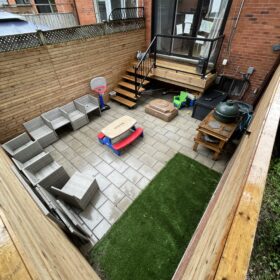 Narrow wooden deck with privacy fencing between two brick buildings, urban home exterior."