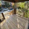 Wooden deck under construction with visible beams and supports in a backyard setting.