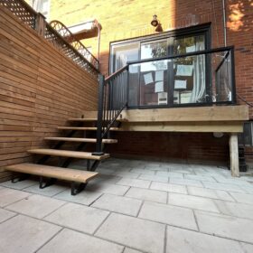 Elevated wooden deck with raised platforms and privacy walls in a residential backyard.