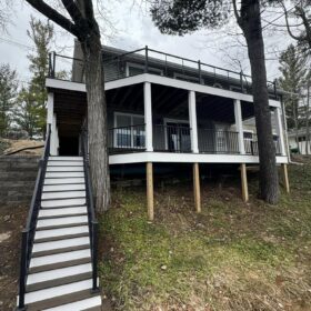 Wooden backyard deck with open railings and stairs leading to a garden