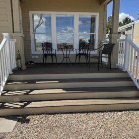 Contemporary wooden deck featuring modern outdoor furniture and wide steps, set against a residential backdrop.