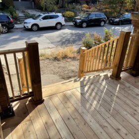 Wooden stairs leading to a covered porch with beautiful shadow patterns on a sunny day.