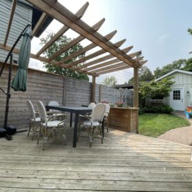 Modern outdoor dining space under a wooden pergola with garden views