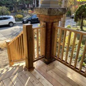 View from a wooden porch overlooking an urban street lined with trees and parked cars, capturing the essence of city living.