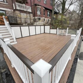 Newly renovated deck with composite flooring and white privacy panels, offering expansive city views.