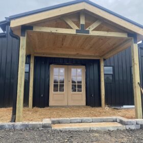 Stylish wooden pergola over patio doors with a striking black and wood color scheme, enhancing the entrance charm.