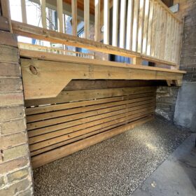 Smart storage solution under a wooden porch utilizing space efficiently with a gravel base and wooden siding.