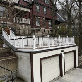 Urban deck built over a garage with white railings, enhancing a vintage red house.