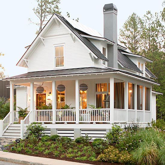 Modern farmhouse with white siding, wraparound porch, black metal roof, and landscaped front yard.