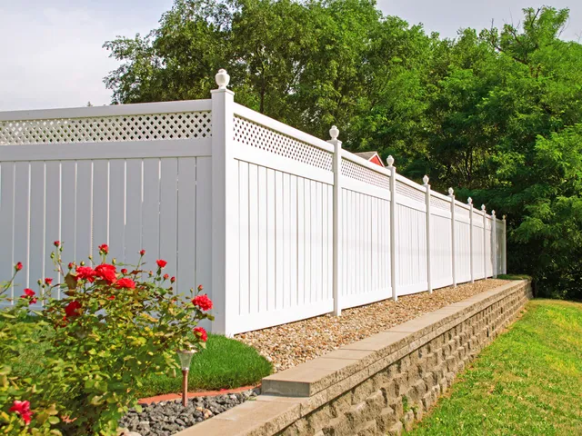 White vinyl privacy fence installed along a backyard lawn.