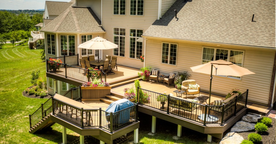 Spacious multi-level backyard deck with seating areas, umbrellas, and black railing