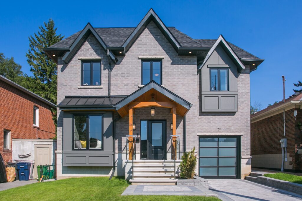 Modern two-story home with brick exterior, black-framed windows, and glass garage door.