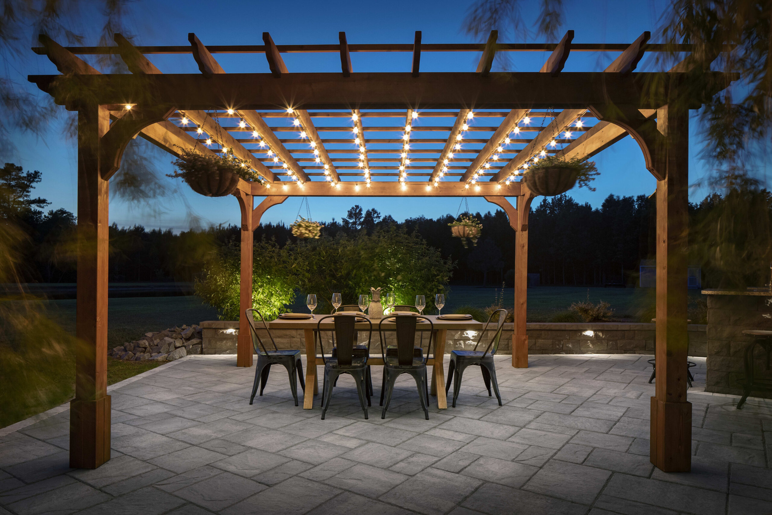 Wooden pergola with string lights over outdoor dining area on stone patio