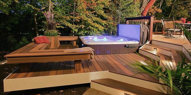 Modern in-ground hot tub with bubbling water built into a wooden deck overlooking a forest.