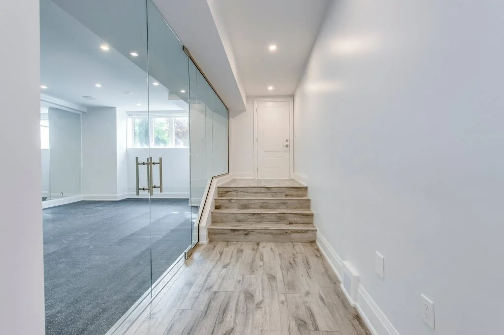 Modern renovated basement with cozy living area, sectional sofa, and carpeted staircase.