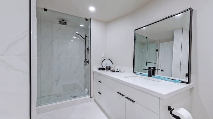 Modern bathroom renovation with glass shower, vanity, and updated fixtures.