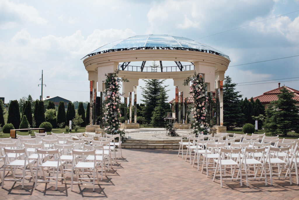 Guest chairs aligned facing wedding archway in garde