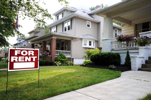 Modern two-story house with a front yard and a red "For Rent" sign, available for lease.