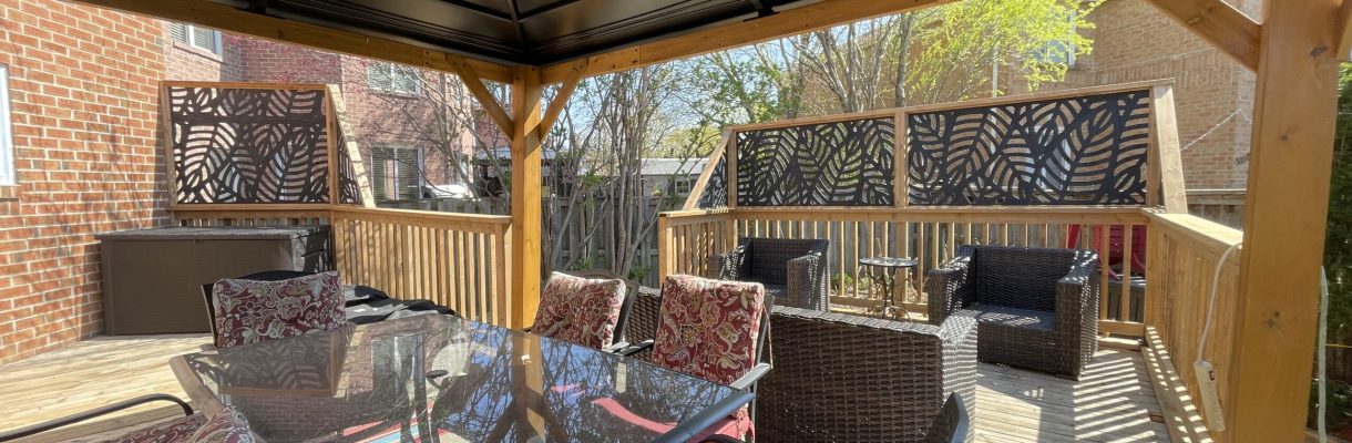 Elegant outdoor dining area under a spacious pergola, surrounded by lush garden and brick walls.