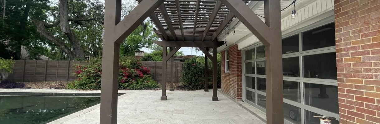 backyard with a dark brown pergola over a paved patio next to a swimming pool